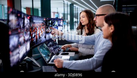 Security Camera System And CCTV Surveillance Monitoring Room: A Young Man Monitors Multiple Screens Stock Photo