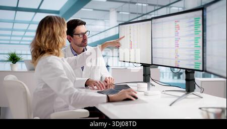 Medical Professionals Reviewing Bill Codes On Multiple Monitors Aggressively. Stock Photo