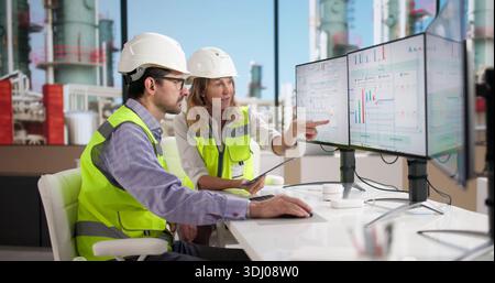 Engineers Using Industrial Energy Monitor At Oil Refinery For Data Analysis Stock Photo