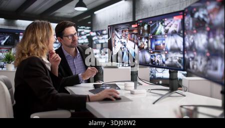 Security Guards Monitoring CCTV Footage In Control Room With Multiple Cameras. Stock Photo