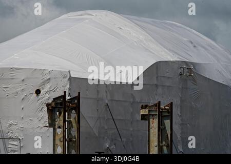 A building is covered in plastic while major repairs are carried out. This protects people walking nearby and the building while it is being repaired. Stock Photo