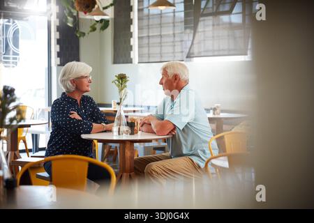 Relax, senior couple and talking in cafe for coffee break, bonding and support in retirement. Love, elderly people and conversation in restaurant for Stock Photo
