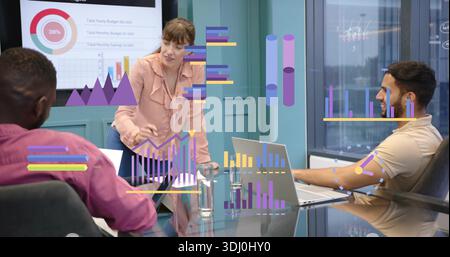 Presenting adult woman in pink blouse leaning gesturing in conference room showing chart overlays Stock Photo