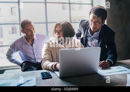 Diverse business managers analyzing data on a laptop during a strategic decision making meeting. Professional team evaluating options, discussing resu Stock Photo
