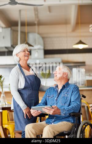 Owners, apron and old people in cafe with tablet, disability and check for price of inventory. Hospitality, tech and managers with wheelchair, stock Stock Photo
