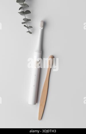 Minimalist flat lay of bamboo and ultrasonic toothbrushes symbolizing conscious lifestyle choice, balance between nature and technology, modern sustai Stock Photo