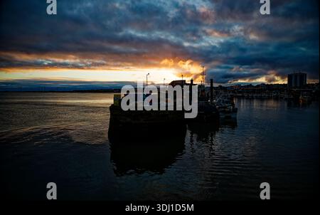 A dramatic moody sunset over the sea and the harbour pier at Bridlington, East Yorkshire, England. Stock Photo