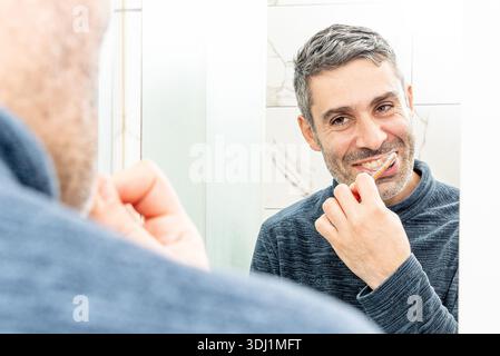 Young man brushing teeth at home in bathroom, lifestyle daily beauty routine Stock Photo