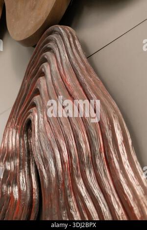 A close view of a wall with a sculptural work shows flowing lines and textures. The light highlights the curves of the piece, creating an interesting Stock Photo
