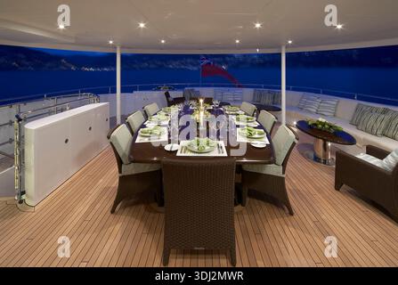 Luxurious Yacht Outdoor Dining On a Long Table Under Night Sky With Ocean View Stock Photo