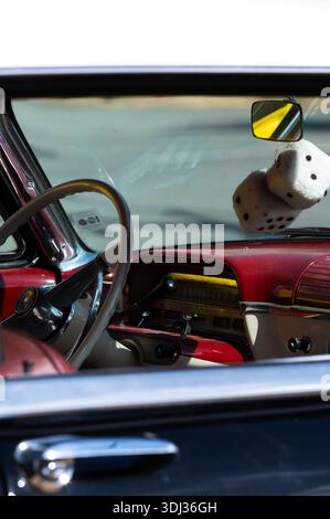 The dashboard and steering wheel of a vintage Mercury automobile are seen through the driver's side window. Chrome accents, analog gauges, and a red-a Stock Photo