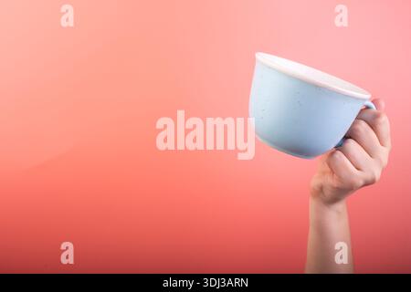 Photo of blue cup coffee in hand isolated on pink background. Banner design. Cup of tea Stock Photo