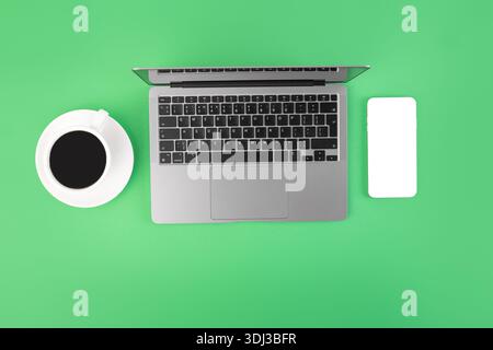 Top view photo of white calculator pen and notebook on grey laptop on isolated green background Stock Photo