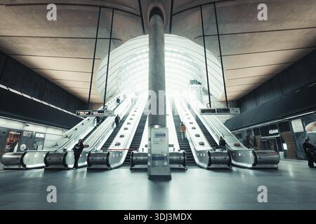 Modern escalators in a train station with symmetrical design and bright lighting, Canary Wharf Station, London, United Kingdom Stock Photo