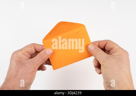 an open orange envelope in the hands on a white surface Stock Photo