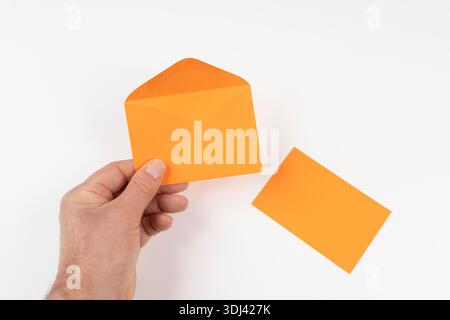 an open orange envelope in the hands on a white surface Stock Photo