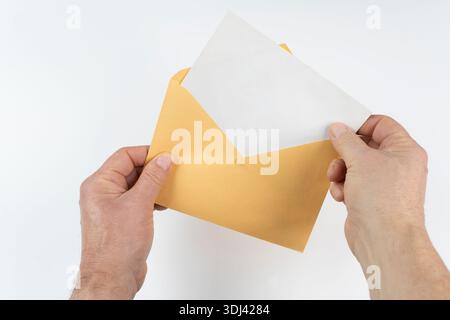 an open yellow envelope in the hands on a white surface Stock Photo