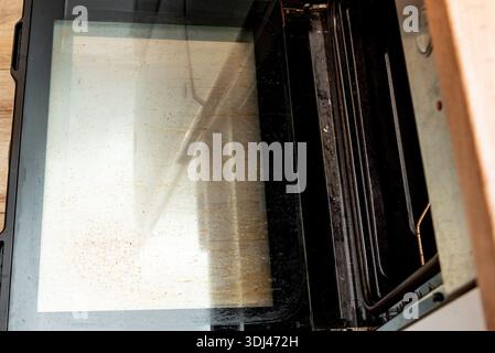 Oven with an open dirty door smeared with old dried grease, kitchen appliances equipment Stock Photo