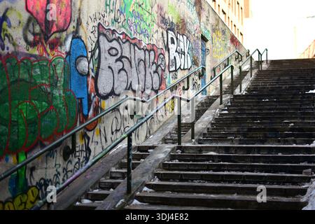 Long concrete stairway with metal railings and graffiti-covered walls. Urban winter scene with snow, strong leading lines, gritty city infrastructure, Stock Photo