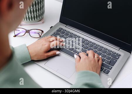 Hands typing on laptop keyboard. Remote work at desk. Online communication and productivity. Modern computer workspace closeup. Stock Photo
