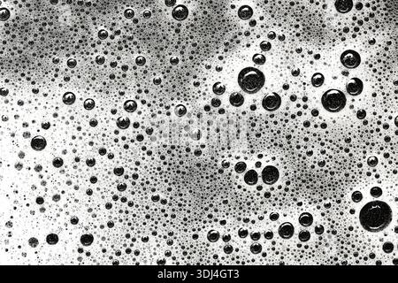 Soap bubbles and foam texture background. Abstract macro surface of cleaning liquid. Detergent or shampoo concept. Black and white liquid pattern. Stock Photo