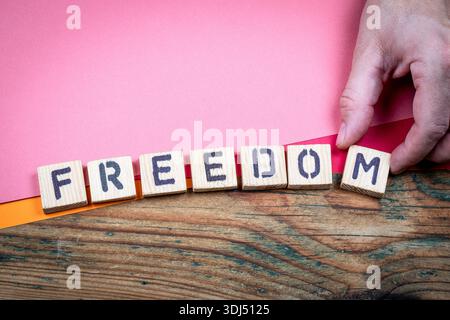 FREEDOM concept shown by wooden letter blocks arranged by hand on wooden surface Stock Photo