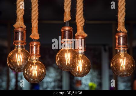 Vintage Edison bulbs with strings, warm ambient lighting and rustic decor. Hung from thick ropes, they create a cozy atmosphere. Stock Photo
