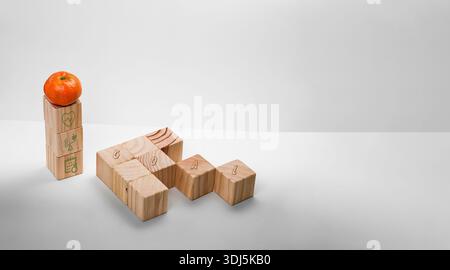 Minimal still life featuring wooden blocks spelling the word goal, with an orange fruit on top of a vertical stack. Concept of personal growth, health Stock Photo
