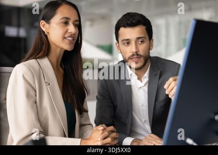 Two colleagues reviewing platform, discussing joint project details on computer Stock Photo