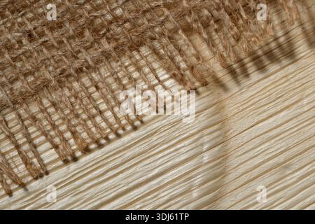 Woven fabric creates an intricate pattern of light and shadow on wood. Stock Photo