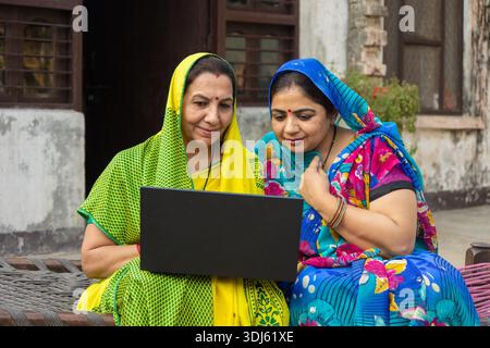Rural indian women using laptop. Two Female friends lear to use computer, online education. Wireless technology. Digital india. Stock Photo