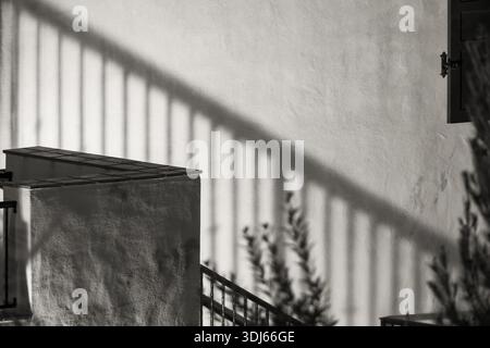 A view of the staircase and the shadow of the railing on the plastered wall. Abstract black and white image Stock Photo