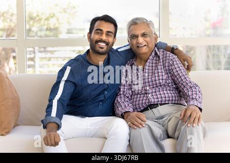 Older man embracing grown-up grandson, posing for family portrait Stock Photo