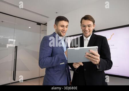 Two businessmen discussing successful project data using tablet Stock Photo