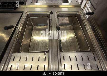 Details with an empty stainless steel professional oil deep fryer in the kitchen of a restaurant. Stock Photo