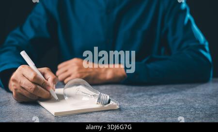 Creative mindset innovation lightbulb idea concept for business insight, professional writes plans with pen while brainstorming vision for project suc Stock Photo