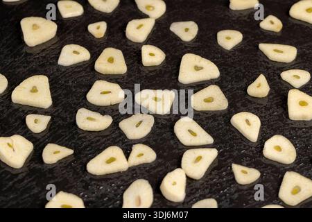 fresh and sliced garlic cloves scattered on black slate, peeled and sliced fragrant natural and fresh spices from garlic cloves scattered on black sla Stock Photo