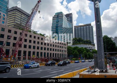 A busy urban street scene with construction work, featuring a crane, modern skyscrapers, and cars driving by Stock Photo