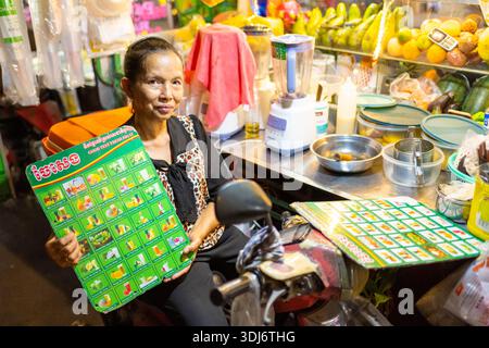 Siem Reap Province,Cambodia-April 02 2025: At a streetfood stall,next to the Siem Reap River in the city center,the woman cooking food tempts passers- Stock Photo