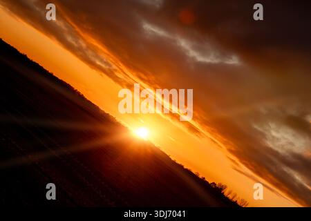 Amazing sunset with golden light on the horizon and heavy clouds above. Dramatic angled viewpoint over a rural landcape in Norfolk England Stock Photo