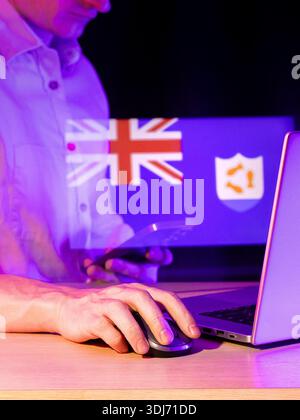 Person handling smartphone while at laptop with mouse, neon purple environment, hologram displaying union flag and protective shield emblem. Stock Photo