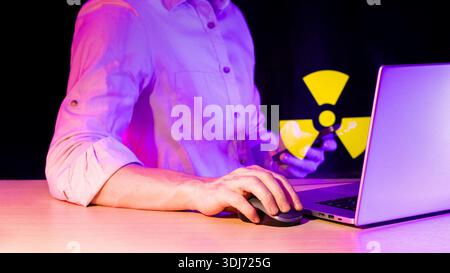 Close-up of hand on mouse beside computer and mobile device with bright yellow hazard symbol Stock Photo
