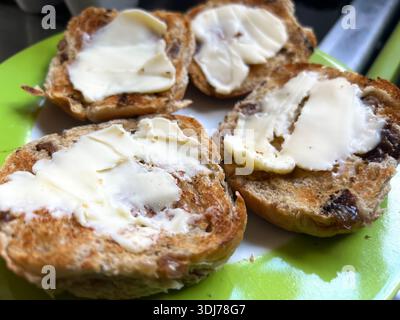 Toasted hot cross buns on a plate topped with butter Stock Photo