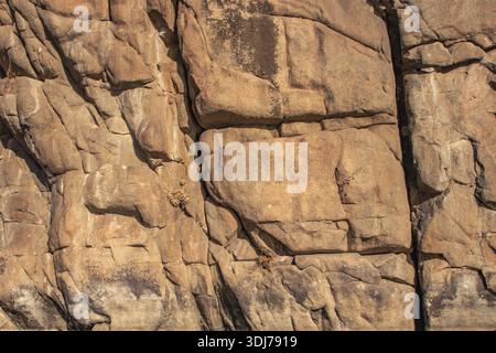 Natural stone wall showing geological layers erosion patterns and rugged surface details formed over time Stock Photo