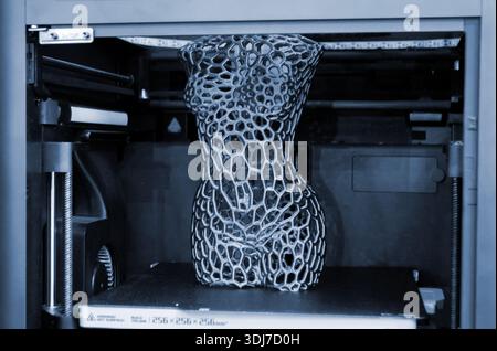Art model printed on 3D printer from molten plastic. Object created on 3D printer inside printer. Form printed on 3D printer from blue plastic on the working surface. Concept 3D printing technology Stock Photo