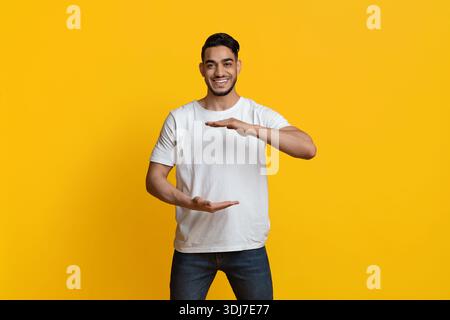 Positive muslim guy holding something invisible in his hands Stock Photo