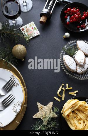 Christmas table set with Christmas decorations, tableware, food, and drinks on a black background. Christmas season and holidays. Christmas concept. Stock Photo