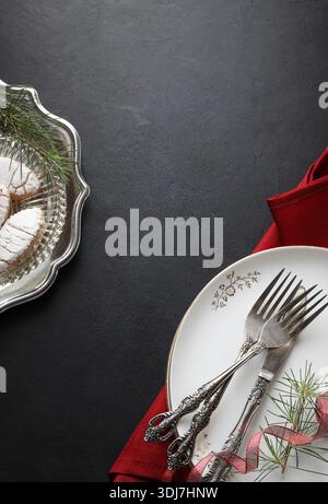 Elegant Christmas table setting with cutlery and plates on a black background. Christmas season and holidays. Christmas concept. Copy space. Stock Photo