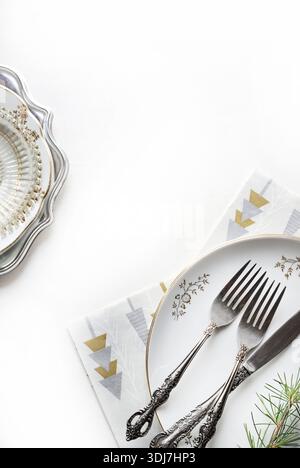 Elegant Christmas table setting with cutlery and plates on a white background. Christmas season and holidays. Christmas concept. Copy space. Stock Photo