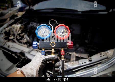 Car air conditioning technician, checks refrigerant and refills air conditioning fluid, car air conditioning service Stock Photo